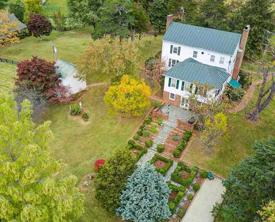 Aerial view of a classic Virginia historic home and surrounding countryside, with mature trees, gardens, and open fields.