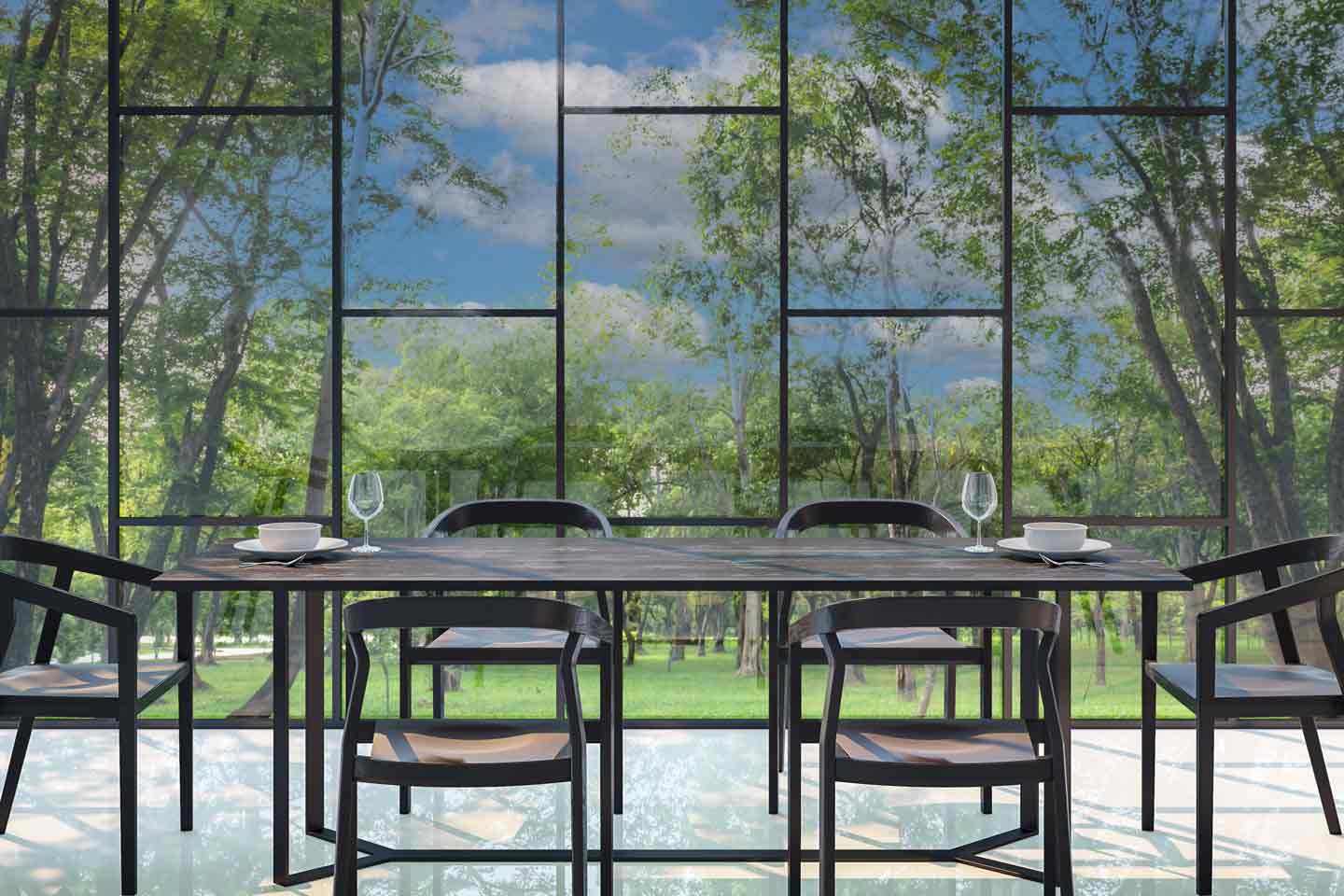 Modern dining area with a sleek black table and matching chairs, set against a floor-to-ceiling glass wall that overlooks a lush green outdoor landscape.