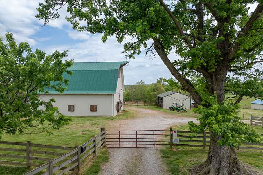 Aerial view of a charming white charlottesville country property with fenced pastures, a barn, and open fields in Charlottesville, Virginia countryside.